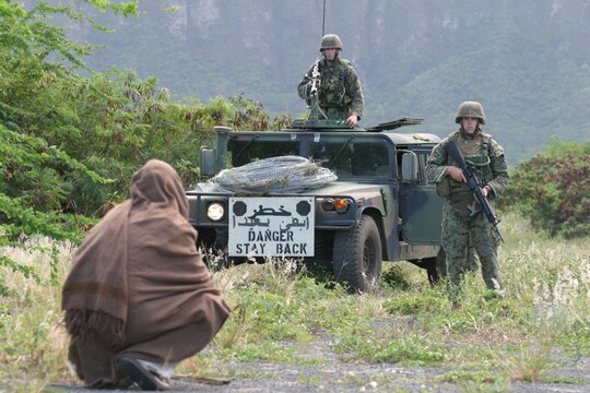 Marines with India Company, 3/3 watch an Iraqi villager, a Marine from 81's Platoon, Weapons Company,  fas he sits near their vehicle during a training evolution Oct. 12 at Marine Corps Training Area Bellows. The villagers posed no threat to the Marines whose objective was to make communication with the village leader and gain information about possible weapons caches, insurgents and upcoming attacks. The village scenerio was one of several training missions the Marines participated in over the course of one day in order to prepare them for their upcoming deployment to Iraq.