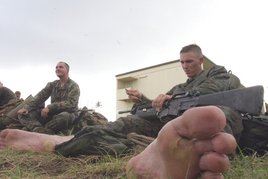 Lance Cpl. Kevin Neale, teamleader, 3rd squad, Lima Company, 3/3, cleans his weapon after the hike from Marine Corps Training Area, Bellows, back to K-Bay.  Neale recieved damage to his feet during the hike.