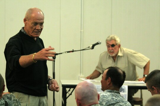 Retired Army Col. Robert L. Howard gives a speech to service members at the Morale, Welfare and Recreation building at Al Asad, Iraq, April 20. Howard received the Medal of Honor March 12, 1968, for his gallant and intrepid actions in the Vietnam War. Leaving his helicopter landing zone and moving out to rescue a missing American soldier, his platoon came under attack by a two-company force. During the initial engagement, he was wounded and a grenade destroyed his weapon. Unable to walk, and seeing his platoon leader wounded, Howard crawled to his leader's aid. After dragging the seriously wounded officer back to the platoon area, Howard was able to rally the disorganized platoon and direct their fire upon the encircling enemy with shouts of encouragement. For three and a half hours, his small force repulsed enemy attacks enough to give rescue helicopters a chance to land. He personally supervised the loading of his men and would not leave the bullet-swept landing zone until all of his soldiers were aboard the helicopters safely.