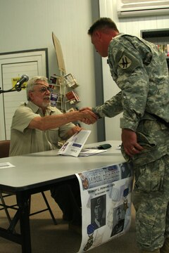 Retired Marine Capt. John J. McGinty III shakes hands with a soldier at the Morale, Welfare and Recreation building at Al Asad, Iraq, April 20. McGinty received the Medal of Honor March 12, 1968, for his gallant and intrepid actions in the Vietnam War. During a four-hour battle in which two of the squads in his 32-man platoon became separated from the rest of his men, he charged through intense automatic weapons and mortar fire to their position. Finding 20 men wounded and the medical corpsman killed, McGinty quickly reloaded ammunition for the wounded men and directed their fire upon the enemy. Becoming wounded in the effort, he never ceased to shout encouragement to his troops, directing their fire to beat the attacking hordes off. When the smoke cleared, the destructive firepower of the artillery and air strikes that he had skillfully directed left an estimated 500 enemy bodies on the battlefield.