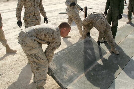 Expeditionary airfield Marines place the last piece of the marshalling pad against the deck at Al Asad, Iraq, April 21. EAF Marines with Marine Wing Support Squadron 274, Marine Wing Support Group 37 (Reinforced), 3rd Marine Aircraft Wing, build these extensions for the taxiways on the airfield to better the flow of air traffic on the flight line.