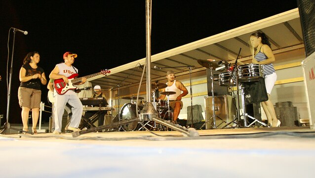 Soto?s percussionist, Lorena Martel, bangs on the ?timbales? drums as the rest of the band watch during her solo spot in one of the songs performed at the concert in Camp Taqaddum, Iraq, August 12, 2006. The band Soto is made up of lead singer Stephanie Alvarado, bassist and co-founder Artie Soto, drummer Joe Mendez, percussionist Lorena Martel, keyboard player Joey Guerra and lead guitarist and co-founder Bruce Soto. The group toured the region playing at a total of nine bases. The band has performed on concert tours with groups such as Earth Wind and Fire, James Brown, Tito Puente,
