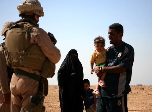 Platoon Sergeant for 1st Platoon, Military Police Company, Combat Logistics Regiment 15, 1st Marine Logistics Group (Fwd) Staff Sgt. Keith S. Littreal talks with an Iraqi family through an interpreter while conducting routine vehicle stops. ?They treat (Iraqi?s) with respect, try to help them out in any way possible.  Offer water and food, ask them how their villages are doing, how their people are doing,? said Littreal, a 29-year-old native of Greensboro, N.C. In the combat zone, MP Company provides security for vehicle/personnel recovery teams, supply trucks, and also scans supply routes for IEDs and enemy activity.
