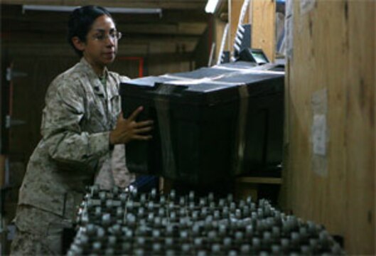 Cpl. Kristine L. Jones, a 23-year-old native of Spring, Texas, sends a parcel down the ramp to an awaiting X-ray machine here July 26, 2006, where it will be scanned for any suspicious content. The post offices here and at seven other locations throughout Iraq and Afghanistan are utilizing X-ray machines to search for items including ammunition (live rounds and spent casings), grenades, shrapnel and magazines for weapons. The systems now in place serve as a precautionary safeguard throughout Iraq and Afghanistan, providing a more accurate way to ensure all mail is thoroughly scanned - and searched if necessary - for contraband before receiving a final X-ray at Bahrain.