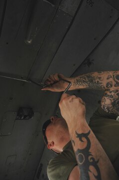Lance Cpl. Kyler Buckner installs the 25 millimeter ammunition chute crossover fairings underneath the belly of an AV-8B Harrier at Al Asad, Iraq, July 10. Buckner, an ordnance technician with Marine Attack Squadron 513, Marine Aircraft Group 16 (Reinforced), 3rd Marine Air Wing, along with the rest of his ordnance shop, is responsible for the munitions on every Harrier at Al Asad. He is a Clarkston, Wash., native.