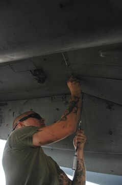 Lance Cpl. Kyler Buckner installs the 25 millimeter ammunition chute crossover fairings underneath the belly of an AV-8B Harrier at Al Asad, Iraq, July 10. Buckner, an ordnance technician with Marine Attack Squadron 513, Marine Aircraft Group 16 (Reinforced), 3rd Marine Air Wing, along with the rest of his ordnance shop, is responsible for the munitions on every Harrier at Al Asad. He is a Clarkston, Wash., native.