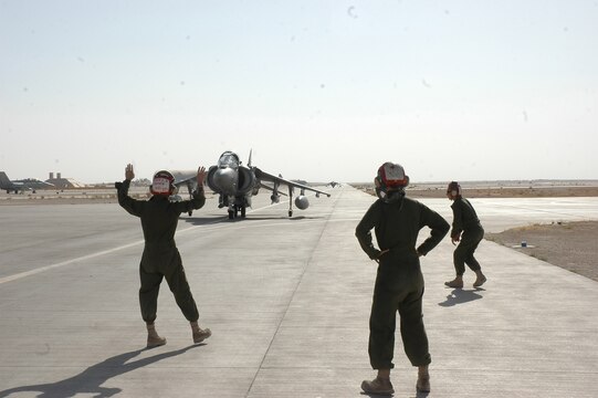 Lance Cpl. Kyler Buckner directs an AV-8B Harrier into a position to arm the weapons on the aircraft at Al Asad, Iraq, July 10. Kyler, an ordnance technician with Marine Attack Squadron 513, Marine Aircraft Group 16 (Reinforced), 3rd Marine Air Wing, and the rest of the ordnance shop, has to arm every Harrier before it takes off, and disarm them when they return from flight.