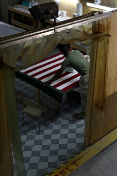 Lance Cpl. Merid Simeon, a personnel recovery and processing Marine at Camp Taqaddum, irons a flag that will be draped over a transfer case used to protect the remains of a service member killed in action, July 19, 2006. The mission of PRP is to inventory the personal effects, identify the types of wounds sustained, and prepare the remains for transportation to Dover Air Force Base. "It's a job we do with respect, and it is an honor to give respect to our fallen brothers and sisters," said Marine Cpl. Jose D. James, a serving with the 1st Marine Logistics Group's PRP detachment. The detachment is comprised of mostly reserve Marines from multiple different military occupations.(Official USMC photograph by Cpl. Stephen Holt. 060719-M-0293H-012. Released.)