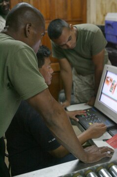 Lance Cpl. John Udui, a 26-year-old native of Waimanalo, Hawaii, and Lance Cpl. Ronnie S. Garcia, a 21-year-old native of Premont, Texas, postal clerks, and Daya Bikram Gurung, a 45-year-old native of Nepal and a civilian X-ray technician, review the digital image of a parcel here July 26, 2006, looking for anything suspicious. The post offices here and at seven other locations throughout Iraq and Afghanistan are utilizing X-ray machines to search for items that include ammunition (live rounds and spent casings), grenades, shrapnel and magazines for weapons. The systems now in place serve as a precautionary safeguard throughout Iraq and Afghanistan, providing a more accurate way to ensure all mail is thoroughly scanned - and searched if necessary - for contraband before receiving a final X-ray at Bahrain.
