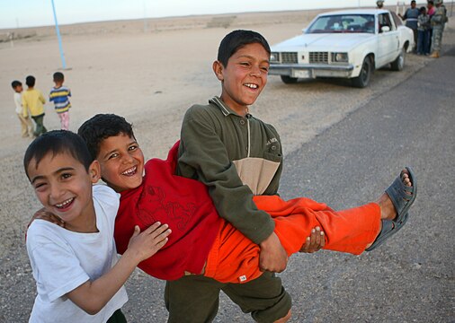 Local Iraqi children have fun while soldiers perform a vehicle search in a village near Camp Taqaddum, Iraq, March 12th, 2006. The soldiers from 2nd Battalion, 130th Infantry Regiment, performed a multi-faceted mission during a daylong operation as they carried out weapons cache sweeps, investigated possible improvised explosive devices and conducted route clearance operations. The Illinois-based National Guard took a few moments throughout the day to assist Iraqi villagers in the area, handing out supplies and spending time with the local children. The soldiers were grateful it wasnâ??t business as usual and could do something a little light hearted. Whether itâ??s handing out candy or searching for IEDs, the soldiers are proud of what they are doing in Iraq, said Sgt. 1st Class Timothy J. Atteberry, platoon sergeant. â??The individual, personal satisfaction of helping another human being really comes from these kinds of humanitarian-aid type missions,â? said Atteberry, a 38-year-old native of Champagne, Ill.::n::::n::The soldiersâ?? primary mission is to provide base security for the Marines and sailors of the forward-deployed 1st Marine Logistics Group. The 4,200 joint-service members of 1st MLG are part of the 25,000 Marines, airmen, solders and sailors of the 1st Marine Expeditionary Forceâ??s forward deployed element. The 1st MLGâ??s mission is to provide sustained logistics support to I MEF and Iraqi security forces operating in the Al Anbar province of Iraq. First MLG will also support the development of the Iraqi Security Forces logistic capabilities in order to enable independent ISF led counter insurgency operations.