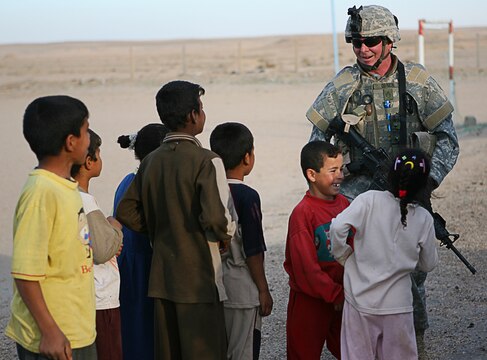 Staff Sgt. Kevin M. Oâ??Brien, infantryman, bridges the language barrier and shares a laugh with a local Iraqi children in a village near Camp Taqaddum, Iraq, March 12th, 2006. Oâ??Brien, 37, of Monticello, Ill., and the other soldiers from 2nd Battalion, 130th Infantry Regiment, performed a multi-faceted mission during the daylong operation as they carried out weapons cache sweeps, investigated possible improvised explosive devices and conducted route clearance operations. The Illinois-based National Guard took a few moments throughout the day to assist Iraqi villagers in the area, handing out supplies and spending time with the local children. The soldiers were grateful it wasnâ??t business as usual and could do something a little light hearted. Whether itâ??s handing out candy or searching for IEDs, the soldiers are proud of what they are doing in Iraq, said Sgt. 1st Class Timothy J. Atteberry, platoon sergeant. â??The individual, personal satisfaction of helping another human being really comes from these kinds of humanitarian-aid type missions,â? said Atteberry, a 38-year-old native of Champagne, Ill.::n::::n::The soldiersâ?? primary mission is to provide base security for the Marines and sailors of the forward-deployed 1st Marine Logistics Group. The 4,200 joint-service members of 1st MLG are part of the 25,000 Marines, airmen, solders and sailors of the 1st Marine Expeditionary Forceâ??s forward deployed element. The 1st MLGâ??s mission is to provide sustained logistics support to I MEF and Iraqi security forces operating in the Al Anbar province of Iraq. First MLG will also support the development of the Iraqi Security Forcesâ?? logistic capabilities in order to enable independent ISF led counter insurgency operations.