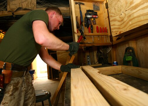 Lance Cpl. Thomas R. Hunter hammers nails while constructing a bench for his 'Gurus' woodshed May 13, 2006, at Al Asad, Iraq. Hunter, a native of Tacoma, Wash., is a combat engineer with Marine Wing Support Squadron 373, Marine Wing Support Group 37 (Reinforced), 3rd Marine Aircraft Wing. Hunter is augmented to Marine Wing Headquarters Squadron 3 for the duration of his deployment and serves as an engineer operations clerk.