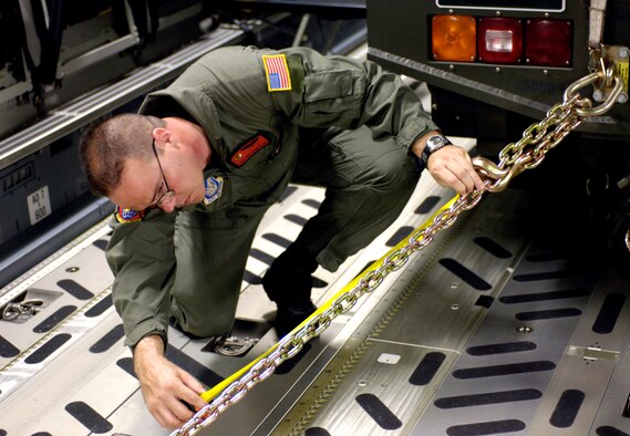 Master Sgt. Mike Cumberland measures a chain securing a vehicle loaded on a C-17 Globemaster III at Hickam Air Force Base, Hawaii, on Thursday, May 25, 2006. Sergeant Cumberland is a loadmaster with the 535th Airlift Squadron at Hickam. He is one of the Air Force crew members helping move equipment and troops from the Solomon Islands to Australia, repositioning Australian Defense Forces to support peace operations in East Timor. (U.S. Air Force photo/Tech. Sgt. Shane A. Cuomo)