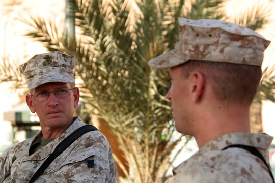 Chief Warrant Officer 3 Gary O. Quinney (left) and his son, Lance Cpl. Gary O. Quinney Jr., sit outside the father's office to catch up with each other before chow at Al Asad, Iraq, Sept. 13. Elder Quinney is the officer-in-charge of the Mortuary Affairs Collection Point Al Asad, Personnel Retrieval and Processing Detachment, Combat Logistics Battalion 7, 1st Marine Logistics Group (Forward). The younger Quinney is a tactical network specialist with communications platoon, Marine Wing Support Squadron 273, Marine Wing Support Group 37 (Reinforced), 3rd Marine Aircraft Wing (Forward). Both, father and son, haven't seen each other for more than two years until their paths crossed in Iraq. The father is a native of Mountain Home, Ark., and the son is a Beaufort, S.C., native.