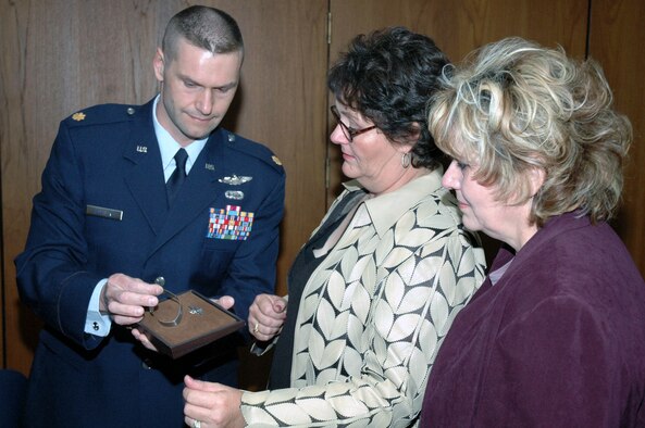 Maj. Phil Heseltine, U.S. Air Force Expeditionary Center executive officer to the commander, Fort Dix, N.J., shows POW/MIA bracelet he wore for 18 years bearing the name of Maj. Robert F. Woods to the daughters of Major Woods during the funeral for Major Woods at Arlington National Cemetery April 9, 2008.  (U.S. Air Force Photo/Tech. Sgt. Scott T. Sturkol)