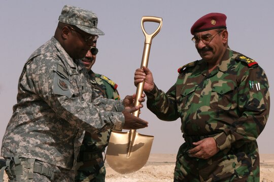 Army Lt. Col. Curt A. Grayer, the senior advisor for the Divisional Training Center here, hands the ceremonial shovel to Iraqi Brig. Gen. Abdullah Mohammad Bayder al-Jabouri, the commanding general of the 7th Iraqi Infantry Division, during a ground-breaking ceremony here today. The ceremony marks the beginning of construction for a new DTC the 7th Iraqi Army Division will have built to enhance formal military instruction.