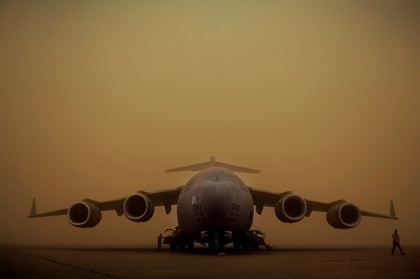 1st Lt. Matheew Lundeen (left) and Maj. Mark Thompson walk around their C-17 Globemaster III April 17 while it's parked on the flight line during a dust storm at Sather Air Base, Iraq. The dust storm reduced visibility to 100 meters and stopped all air traffic. (U.S. Air Force photo/Tech. Sgt. Jeffrey Allen)