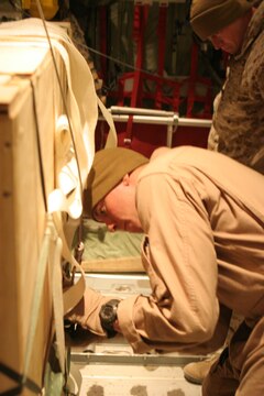 Cpl. Matthew L. Sandford, 21, Chippewa Falls, Wis., load master, Marine Aerial Refueler Transport Squadron 352, Marine Aircraft Group 11, 3rd Marine Aircraft Wing, inspects a container delivery system on a KC-130J aircraft prior to takeoff here, Dec. 26. Combat Logistics Battalion 2, 1st Marine Logistics Group and VMGR-352 conducted an aerial resupply delivery to Bravo Company, 1st Reconnaissance Battalion, Regimental Combat Team 5 in northwestern Iraq. ?The only way that we can resupply Reconnaissance Marines is by conducting air deliveries,? said Cpl. Mathew J. Ladd, 21, Bowling Green, Ky., air chief, CLB-2, 1st MLG. ?Bravo Co. is limited to what they can carry because they need to maintain maneuverability to complete their mission.? The Recon Marines were resupplied with food, water and vehicle repair parts. As soon as the KC-130J pilots neared the Bravo Co. position, they lowered the plane to several hundred feet above the ground, opened the ramp and accelerated at an incline so the bundles would slide down the rollers and out the back of the aircraft. ?The parachutes initiate right as the bundles fall out of the plane,? said Maj. Brian J. Gilbertson, 33, Waukesha, Wis., executive officer/pilot, VMGR-352, MAG-11, 3rd MAW. ?It takes roughly 400 ft. for the parachutes to fully bloom.? Once the four 1,500 pound bundles landed, Bravo Co. collected the supplies and folded the parachutes so they could be used again. Combat Logistics Battalion 2 provides western Iraq with all air resupply deliveries.