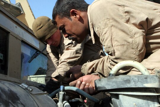 Cpl. Jaimey C. Syvruv, motor transportation mechanic, Combat Logistics Battalion 2, 1st Marine Logistics group, helps an Iraqi Soldier trouble shoot a heater problem on a High-Mobility, Multipurpose, Wheeled Vehicle during the first Iraqi partnership at the Iraq camp here, Dec. 31. ?This is the first time we worked with Iraqi Soldiers at their camp instead of our maintenance area,? said Gunnery Sgt. Duane E. Black, 38, Marceline, Mo., Motor Transportation Maintenance Platoon commander, CLB-2, 1st MLG. ?We can train more of their mechanics at the Iraqi maintenance bay because they all can?t come over to our shop.? For more than a year, Iraqi mechanics on Camp Majed aboard Al Asad have been traveling to the American side of the base for HMMWV mechanical training. No more then five Iraqi Soldiers would show up every Wednesday to learn about fixing their military vehicles. Over the last year, the Primary Iraqi Command has been focusing on Marines standing back and advising instead of fixing the vehicles for them. ?We?re here to watch over the Iraqi Soldiers and observe them work on HMMWV,? said Syvruv, 22, Blanchardville, Wis. ?We are standing back and letting them do the work so they can become more self sufficient.? With all the mechanical knowledge the Marines taught to the Iraqi Soldiers, U.S. forces will be able to leave Iraq knowing they can function as a military on their own.