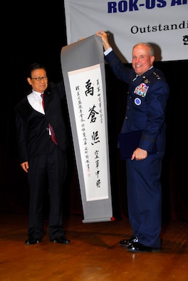 OSAN AIR BASE, Republic of Korea--Chairman Suh Jin Sup of the Korea-U.S. Alliance Friendship Society gave the Seventh Air Force Commander Lt. Gen. Stephen G. Wood the name "Woo, Chang Hui." (Pronounced Woo, Chang Hee.) during a naming ceremony witnessed by the Chief Master Sergeant of the Air Force Rodney J. McKinley and approximately 200 Airmen, Soldiers, Sailors, and Marines and ROK civic leaders.  The naming ceremony was part of a larger recognition ceremony where 45 Korean leaders presented 50 Airmen certificates embossed with the gold letters "ROK-US."  (U.S. Air Force photo/Senior Airman Christopher Boitz)