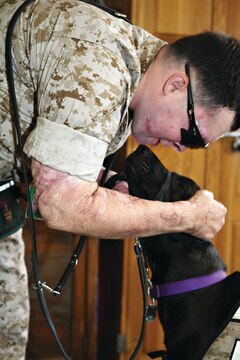 Cpl. Christopher Gray praises Rocio, his newly trained assistance dog, for a job well done. Rocio is one of the first dogs to graduate from a unique program at the base brig.