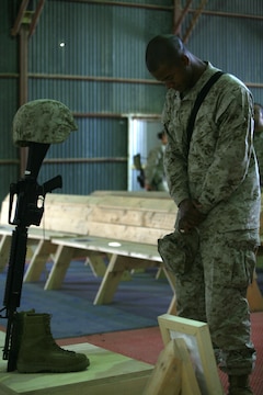 Cpl. Dandre M. Locrox, 23, from Stone Mountain, Ga., section head for the Ammunition Supply Point, 1st Maintenance Battalion (-) (Reinforced), 1st Marine Logistics Group, pays his final respects to his friend and fellow Marine, Lance Cpl. Stacy Ann Dryden during a memorial ceremony here, Oct. 27. Dryden, 22, from North Canton, Ohio, was serving in Iraq as a preservation, packaging and packing specialist when she died Oct. 19 from a non-combat related incident in al Anbar Province, Iraq.