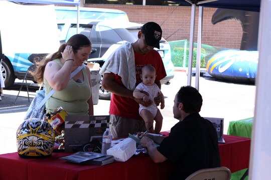 The Guardado family stops to speak to Jeff Gordon, general manager, K1 Speed, at the ITT Latitudes & Travel Expo, Aug. 14. Staff Sgt. Alberto Guardado, section leader, Aircraft Rescue Firefighting, Marine Corps Air Station Camp Pendleton, attended the expo with his wife, Mindy, 3-year-old daughter Elizabeth and 5-month-old son Alberto.