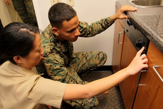 Lt. Cmdr. Leah Y. Geislinger, assistant department head, Physical and Occupational Therapy Department, Naval Hospital Camp Pendleton, walks Lance Cpl. Emilio A. Vasquez, one of the first two ADL apartment patients with 1st Supply Battalion, 1st Marine Logistics Group, through proper dishwashing steps at the opening of the Marine Corps’ first rehabilitation apartment at Camp Pendleton’s Naval Hospital, Dec. 11.