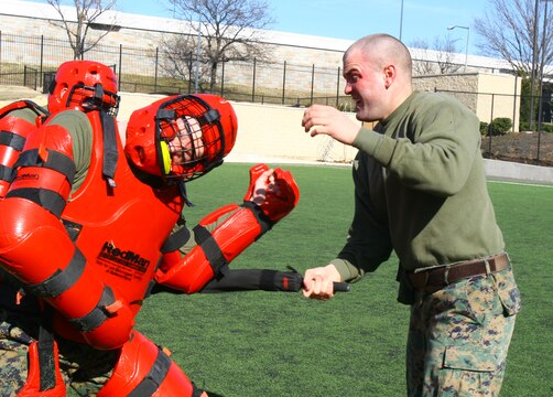 Cpl. David Chancellor, guard, Marine Barracks Washington, confronts two training dummies after being sprayed with a potent chemical during nonlethal tactics training at Marine Barracks Washington, Feb. 17. Chancellor, among others, qualified as a user and instructor of oleoresin capsicum, or OC spray.