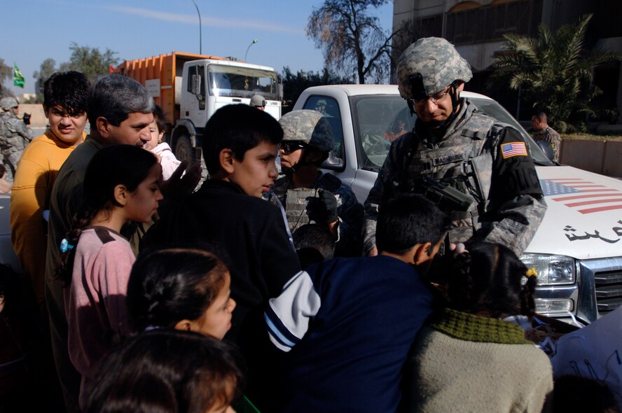 Capt. Ben Washburn hands out toys, school supplies and clothes while on foot-patrol in an apartment complex Jan. 10 in the International Zone of Baghdad, Iraq. The items were gathered by a group of volunteer servicemembers at Joint Base Balad, Iraq, called the Kids of Iraq. The items come from donators in the United States. Captain Washburn is the 732nd Expeditionary Security Forces Squadron Det. 4 operations officer. He is deployed from Vogelway, Germany, and is a native of Colorado Springs, Colo. (U.S. Air Force photo/Tech. Sgt. Craig Lifton) 
