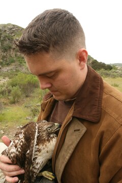 Sgt. Thomas Parker, a ground safety manager with Marine Light Attack Helicopter Training Squadron 303, Marine Aircraft Group 39, 3rd Marine Aircraft Wing, clutches his red tail hawk, Akando in an attempt to calm him down near Oceanside, March 14. The Houston native captured the bird more than a month ago and has spent much of his free time training him to better catch prey.  (U.S. Marine Corps photo by Lance Cpl. Christopher O'Quin) (Released)
