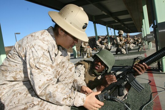 Cpl. Erika Scott, a combat marksmanship coach and administrative clerk with Headquarters and Headquarters Squadron Marine Corps Air Station Miramar, helps Lance Cpl. Antwan D. Wilson, an administrative clerk with Headquarters and Headquarters Squadron, find his settings for the table two field fire section of rifle qualification at the Carlos Hathcock Range Complex.  Units can provide their own coaches to assist with training and qualifying shooters.   (U.S. Marine Corps photo by Lance Cpl. Christopher O'Quin) (Released)