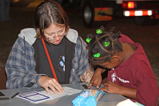 Lance Cpl. Jamie Anderson, military working dog handler at the Provost Marshal’s Office here, helps a young girl take her fingerprints for a children’s identification kit during the annual Matthew C. Perry Fall Festival held at the M.C. Perry soccer fields here Oct. 16. PMO also allowed the children to tour their mobile command center.
