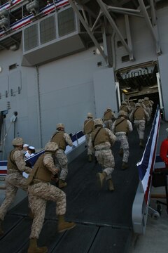Marines with I Marine Expeditionary Force rush aboard the gangplank of the USS Makin Island (LHD-8) during its commissioning ceremony, here Oct. 24. As an amphibious assault ship, this part of the ceremony signifies the Marines bringing the ship to life for service in the Fleet.