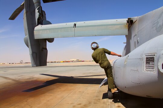 Lance Cpl. Mark Moretz, with Marine Medium Tiltrotor Squadron 261, 3rd Marine Aircraft Wing (Forward), here, climbs up to get a better look at the wing and rotor during preinspection of an MV-22 Osprey ensuring the bird is ready for a full day of missions, April 24.