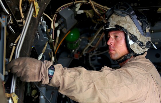 Staff Sgt. John Godwin, a Loxley, Ala., native serving as a flight equipment technician and aerial observer with Marine Medium Tiltrotor Squadron 261, 3rd Marine Aircraft Wing (Forward), here, plugs in a wire he will use to communicate with the pilots as he and the MV-22 Osprey crew conduct missions in the region, April 24.
