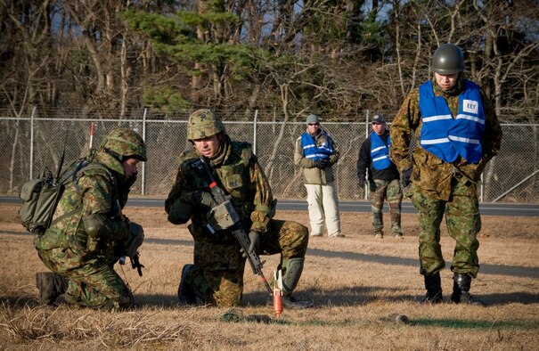 Soldiers from Japan Ground Self Defense Force, 9th Strikethrough Division, 5th Infantry Regiment, Aomori, examine simulated unexploded ordnance, Dec. 4, 2010, at Misawa Air Base, Japan, while members from the JGSDF and 35th Security Forces Squadron emergency evaluation team members evacuate their response measures. (U.S. Air Force photo by Senior Airman Jessica Lockoski) 