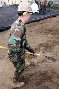 Petty Officer 3rd Class Joshua T. Mynear, equipment operator, Alpha Company, Amphibious Construction Battalion 1, Naval Construction Force, clears the area surrounding a newly built Marine Corps Martial Arts Program pit, where Field Medical Training Battalion West students can train in MCMAP. The pit is located at Camp Del Mar, Camp Pendleton, and is designed to reduce injuries and promote safety. In addition, Seabees have also gained valuable training in their job field by building the pit.