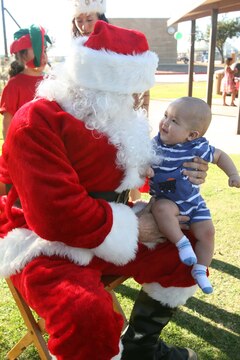 Ayden Dukes, six-month son of Gunnery Sgt. Darren Dukes, sits on Santa's lap at the Marine Wing Support Group-37 Family Holiday Day at Mills Park here Dec. 12. There was an ornament-making station, an inflatable bounce house, and food and drinks for families to enjoy.