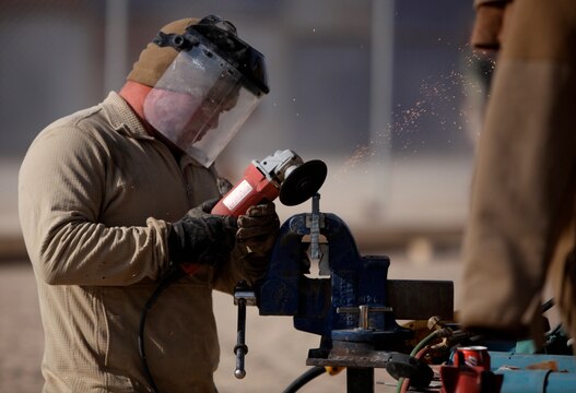 Lance Cpl. Robert Hill, welder, Support Company, 8th Engineer Support Battalion, 1st Marine Logistics Group (Forward), grinds a piece of steel at Camp Leatherneck, Afghanistan, Dec. 21. The service members with 8th ESB built a bridge out of steel and wood that will serve as a permanent replacement for a medium girder bridge in Marjah.