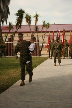 Sgt. Maj. Antonio N. Vizcarrondo Jr. holds his grand daughter as he speaks to Marines and sailors of 1st Marine Logistics Group during his acceptance speech after being appointed 1st MLG Sergeant Major.