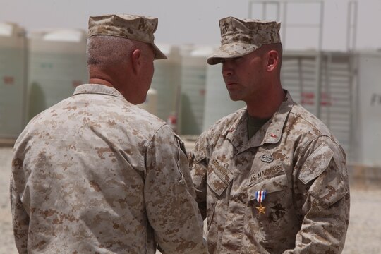 Warrant Officer John Hermann, 32, from Tucson, Ariz., explosive ordnance disposal officer for 1st Explosive Ordnance Disposal Company, 1st Marine Logistics Group (Forward), is congratulated by Brig. Gen. Charles L. Hudson, commanding general of 1st MLG (FWD), after being awarded the Silver Star medal in a ceremony at Forward Operating Base Delaram II, Helmand Province, Afghanistan, July 15. In February 2008, Hermann was deployed to Afghanistan as an EOD technician when his element came under enemy fire in the village of Dahaneh, Afghanistan. One of his fellow Marines was shot in the leg while running behind him.  Ignoring his own shrapnel wounds from a rocket propelled grenade, Hermann “single-handedly destroyed the enemy assailants, and then crossed back through the machine gun fire of another enemy position in order to treat his fallen comrade,” according to his Silver Star citation. He applied a tourniquet to the wounded Marine’s leg, then took charge of the Marines to establish a security cordon and evacuate the Marine to safety. Hermann was later promoted to gunnery sergeant and then selected for the warrant officer program. He has served in the Marine Corps 14 years.