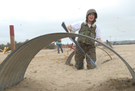 Brittony Arledge, Special Education Facilitator, Centennial High School, North Las Vegas, Nev., discovers humor helps her through her difficulty on the bayonet assault course, of crawling through the sand and dirt while carrying a rifle and wearing a flak-jacket and Kevlar helmet during the educators workshop on MCRD San Diego.