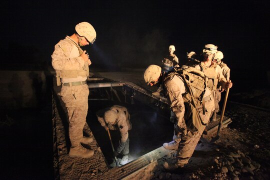 Marines with Bridge Platoon, Company A, 9th Engineer Support Battalion, 1st Marine Logistics Group (Forward), assist a fellow Marine as he digs out debris from under a bridge during a bridge replacement project in Marjah, Afghanistan, Oct. 23. The Marines removed an old medium girder bridge and replaced it with a newer one, to be used by coalition forces and local nationals.