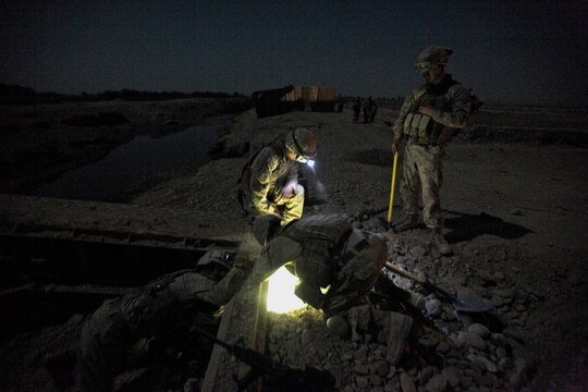 Marines with Bridge Platoon, Company A, 9th Engineer Support Battalion, 1st Marine Logistics Group (Forward), assist a fellow coworker as he digs out debris from under a bridge during a bridge replacement project in Marjah, Afghanistan, Oct. 23. The Marines removed an old medium girder bridge and replaced it with a newer one, to be used by coalition forces and local nationals.