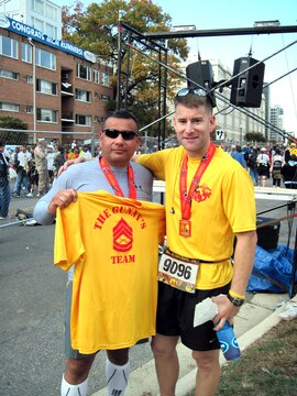 Gunnery Sergeant John Caraway (left), who was diagnosed with cancer in April, holds up his support team’s shirt with Major Brian Rideout at the Marine Corps Marathon on Oct. 31.