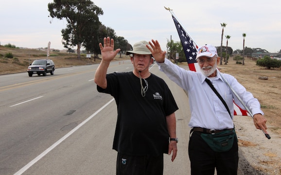 Anthony A. LoBue, better known as Tony the Vet (right) and his close friend Robert F. Satterfield, a retired Navy chaplain, wave to supporters on Camp Pendleton Sept. 28. Tony is walking across America in hopes to be at Ground Zero, by Sept. 11, 2011.
