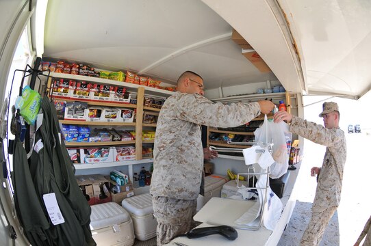 Staff Sgt. Jose Bugarin, left, Marine Corps Community Services retail staff noncommissioned officer, hands Petty Officer 3rd Class Jacob Gill, Marine Wing Communications Squadron 28 corpsman, his purchases at the mobile post-exchange at Site 50 in the Barry M. Goldwater Range in Arizona, April 12, 2011.