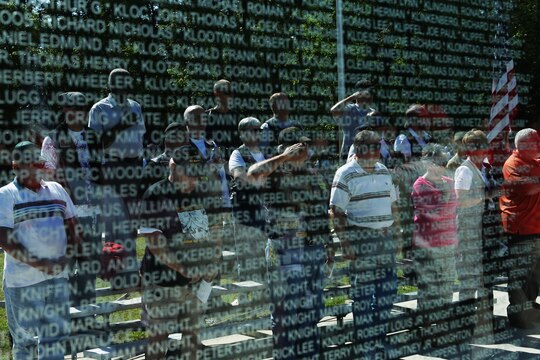 Service members, friends and family can be seen through the walls of the Vietnam War memorial at the Lejeune Memorial Gardens during the annual Vietnam Remembrance Day ceremony, April 29. The event was to celebrate the service men and women who returned from the jungles of Vietnam and to remember those who did not.