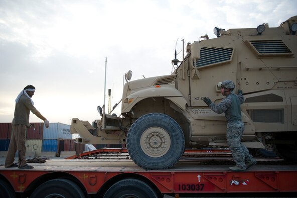 U.S. Air Force Senior Airman, Ryan Baker, a native of Fishers, IN., works with a contractor to align a mine-resistant ambush protected on a trailer at Forward Operating Base Warrior on Oct. 27, 2011. Baker is deployed from Hurlburt Field, Fla., is responsible for driving an M915 tractor in a convoy of 43 vehicles with 60 passengers more than 1,100 miles through Iraq. Members of the 70th MTD are hauling equipment out of Iraq to meet the deadline for the U.S. military transition from Iraq. (U.S. Air Force Photo/Master Sgt. Jeffrey Allen)